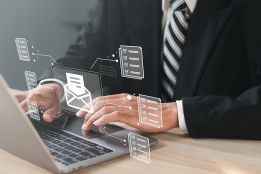 Foto: Mann vor Laptop mit schwebendem digitalen Brief über der Tastatur