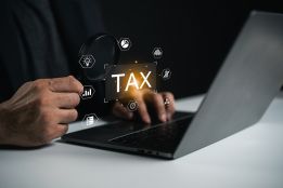Foto: Geöffneter Laptop mit Schriftzug TAX darüber